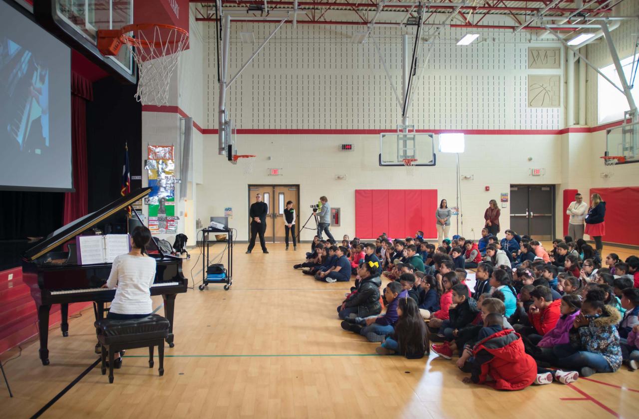Children watch a host and pianist at a Cliburn in the Classroom program