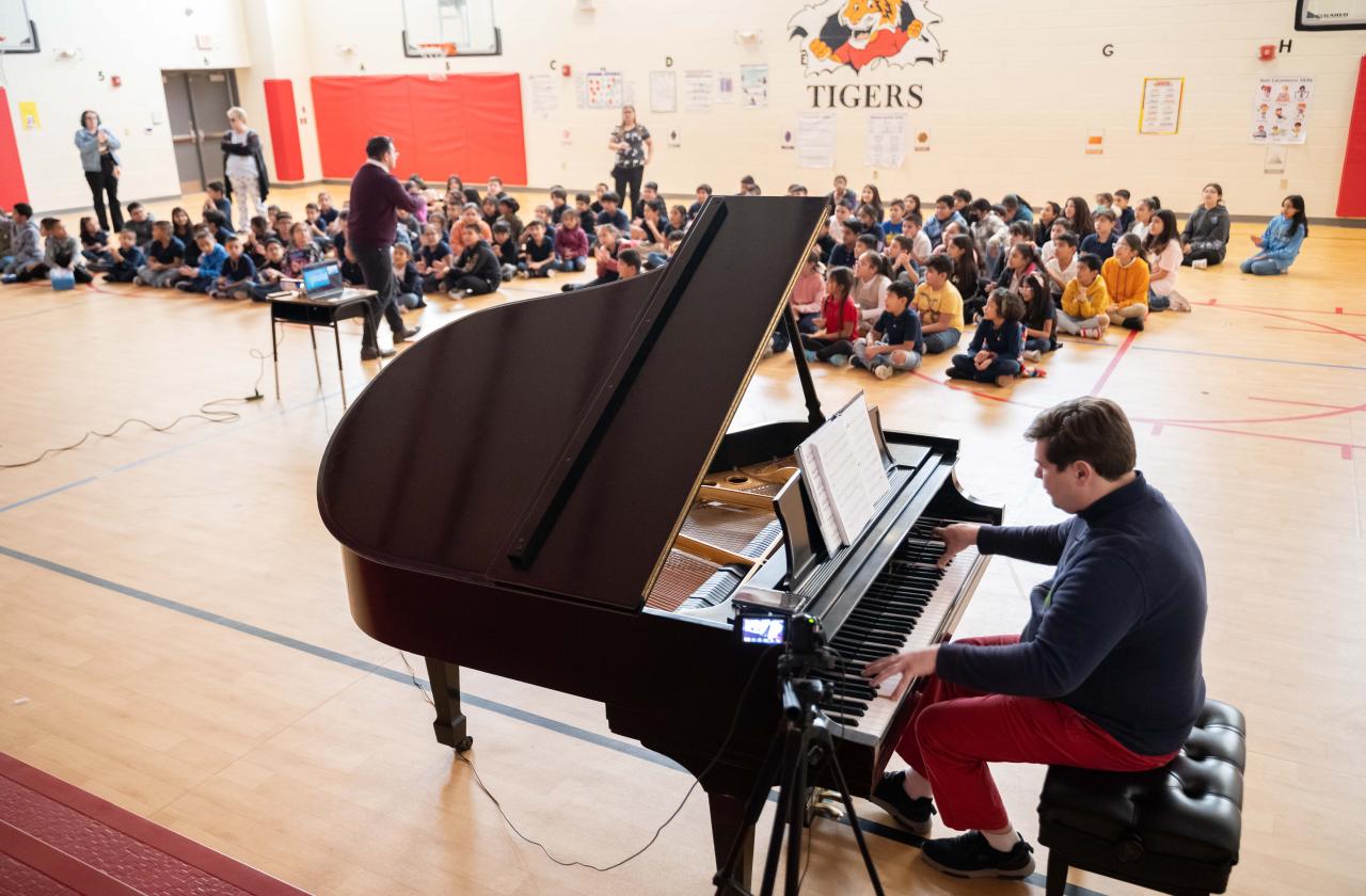 Children watch a host and pianist at a Cliburn in the Classroom program