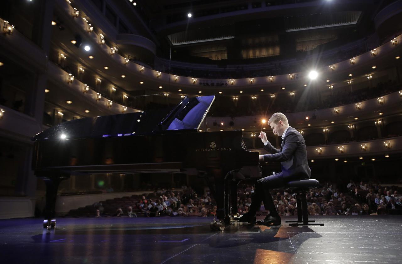 Dmytro Choni playing the piano with the lights and audience behind him
