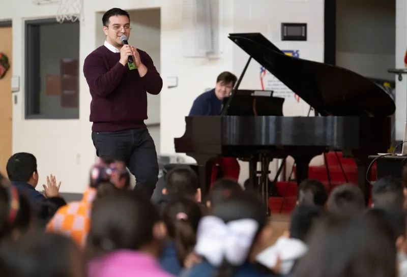 A host and pianist perform Cliburn in the classroom for a group of elementary students